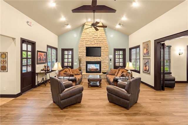 living room featuring a fireplace, light wood-type flooring, high vaulted ceiling, and ceiling fan