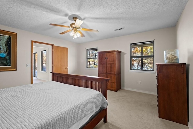 carpeted bedroom featuring multiple windows, ceiling fan, and a textured ceiling