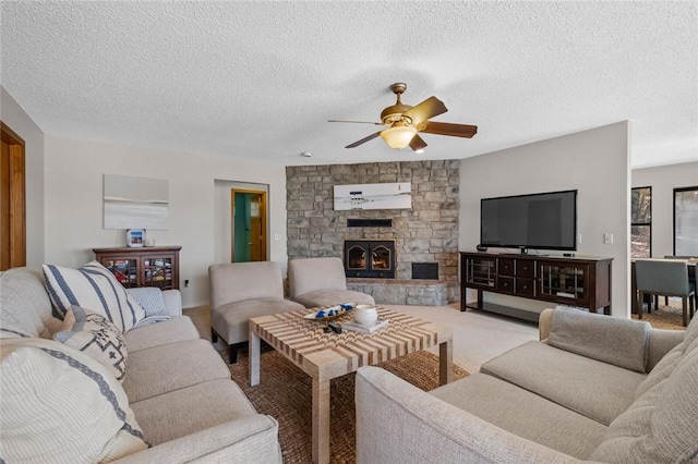 living room featuring ceiling fan, a fireplace, and a textured ceiling