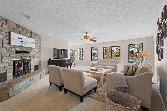 living room featuring a textured ceiling, a fireplace, ceiling fan, and light carpet