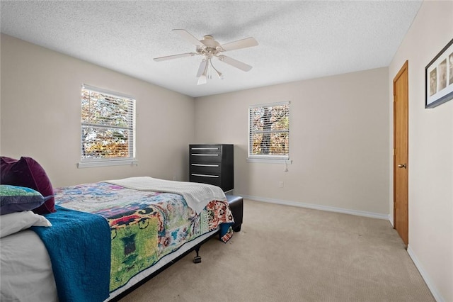 bedroom with ceiling fan, light colored carpet, and a textured ceiling