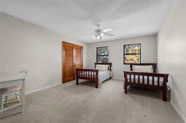 carpeted bedroom featuring ceiling fan and a textured ceiling