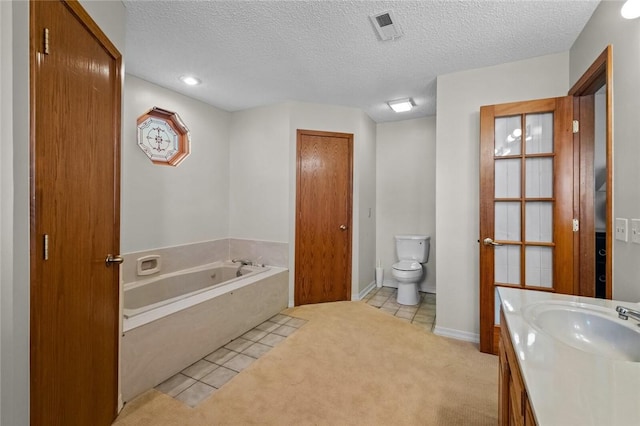 bathroom featuring a washtub, tile patterned floors, a textured ceiling, toilet, and vanity