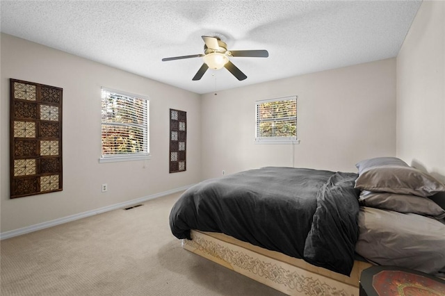 carpeted bedroom with multiple windows, ceiling fan, and a textured ceiling