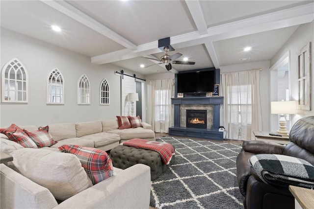 living room featuring beamed ceiling, ceiling fan, and a barn door