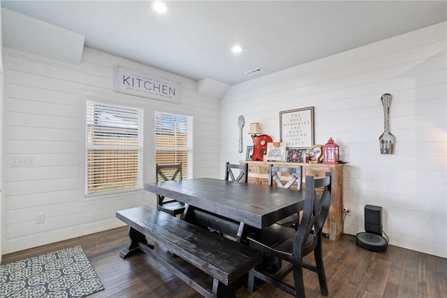 dining room featuring dark hardwood / wood-style flooring and wooden walls