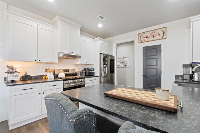 kitchen with backsplash, hardwood / wood-style floors, a breakfast bar, white cabinets, and appliances with stainless steel finishes