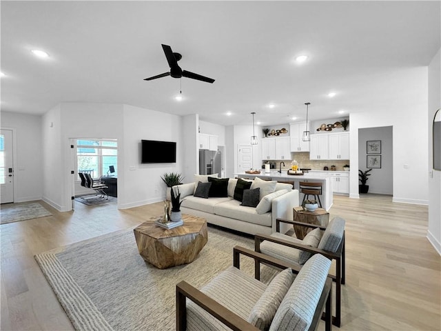 living room with recessed lighting, light wood-type flooring, baseboards, and ceiling fan