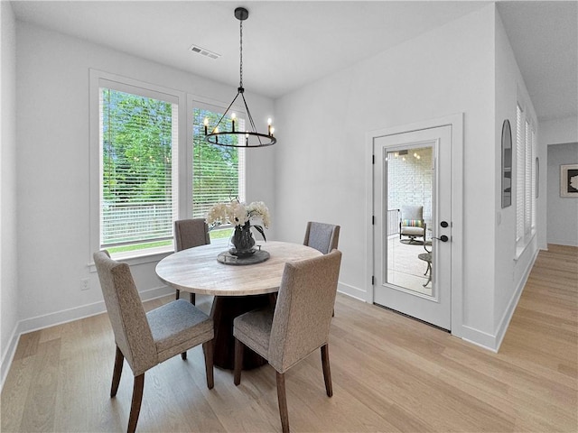 dining space with visible vents, baseboards, a notable chandelier, and light wood-style flooring