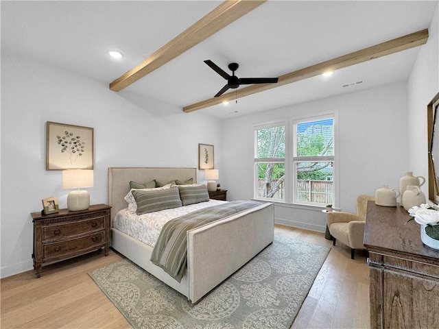 bedroom featuring light wood-type flooring, beam ceiling, baseboards, and visible vents