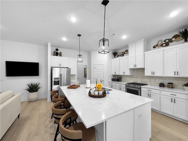 kitchen with light wood finished floors, tasteful backsplash, stainless steel appliances, white cabinetry, and a sink