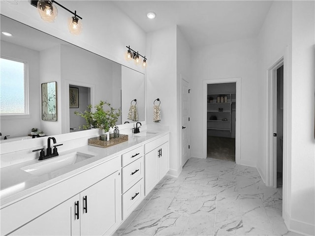 full bath with double vanity, marble finish floor, baseboards, and a sink