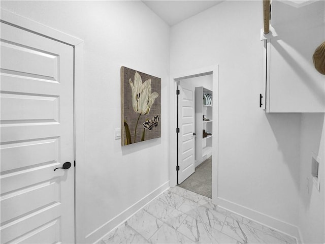 corridor with marble finish floor and baseboards