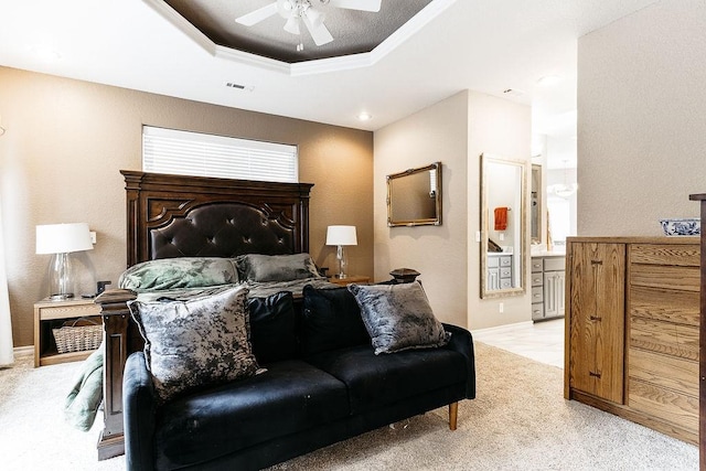 carpeted bedroom with ensuite bathroom, a raised ceiling, ceiling fan, and ornamental molding