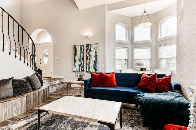 living room with a wealth of natural light, hardwood / wood-style floors, and a towering ceiling