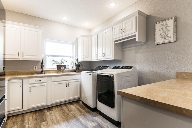 laundry area featuring washing machine and dryer, dark hardwood / wood-style flooring, cabinets, and sink