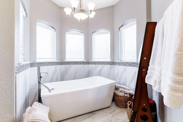 bathroom with a chandelier, plenty of natural light, and tile walls