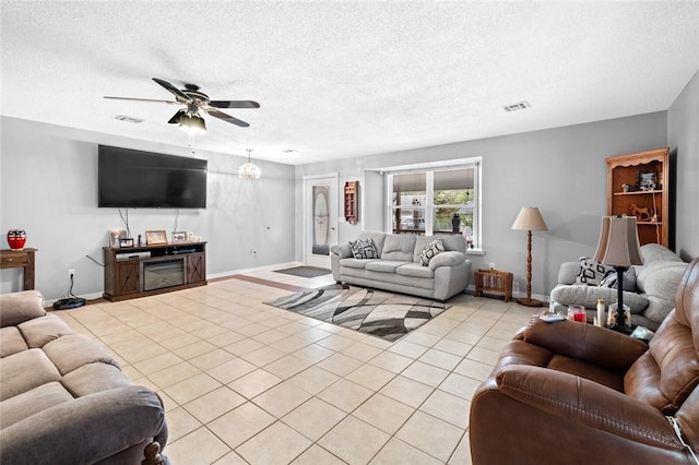 living room with ceiling fan, light tile patterned floors, and a textured ceiling