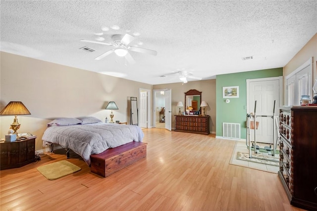 bedroom with ceiling fan, light hardwood / wood-style floors, and a textured ceiling