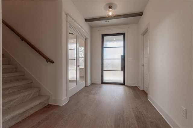 foyer entrance featuring beam ceiling, hardwood / wood-style flooring, and french doors