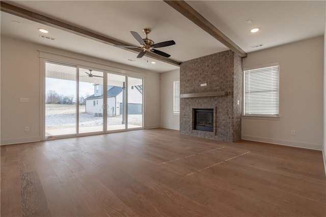 unfurnished living room featuring beam ceiling, ceiling fan, a fireplace, and hardwood / wood-style floors