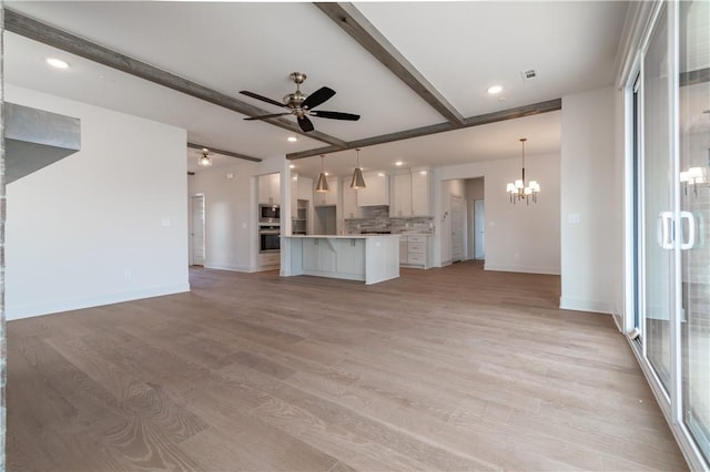 unfurnished living room with beamed ceiling, light hardwood / wood-style floors, and ceiling fan with notable chandelier