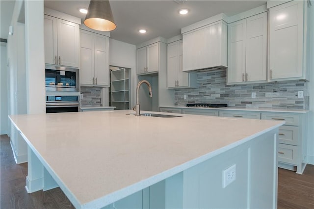 kitchen featuring decorative backsplash, appliances with stainless steel finishes, white cabinetry, and an island with sink