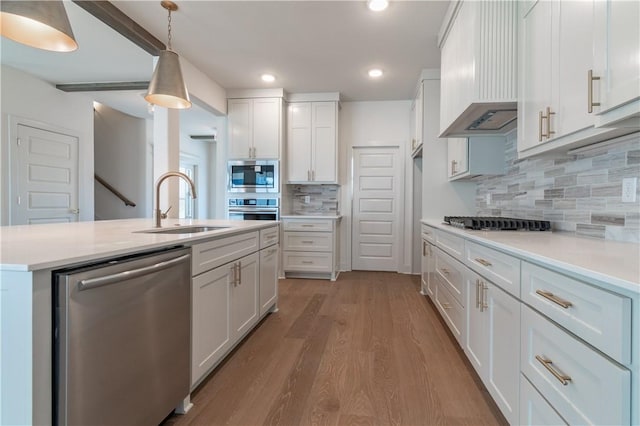 kitchen featuring white cabinets, wall chimney exhaust hood, stainless steel appliances, and hanging light fixtures