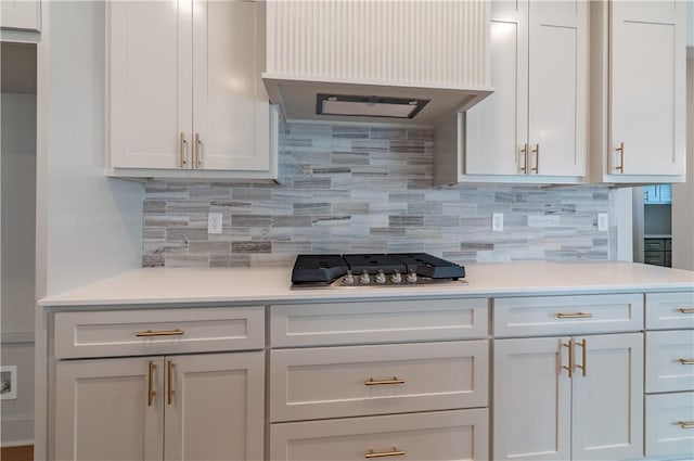 kitchen with tasteful backsplash, white cabinetry, and range hood