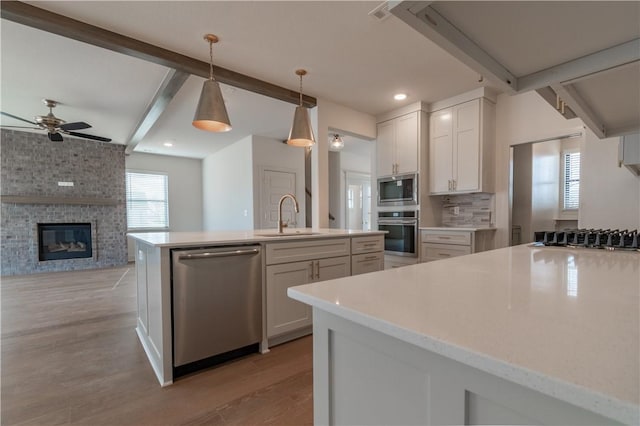 kitchen with white cabinetry, sink, stainless steel appliances, and decorative light fixtures