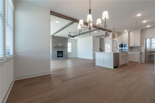 kitchen with white cabinetry, hanging light fixtures, an island with sink, ceiling fan with notable chandelier, and appliances with stainless steel finishes