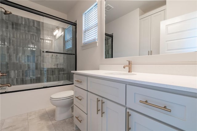 full bathroom with combined bath / shower with glass door, vanity, and toilet