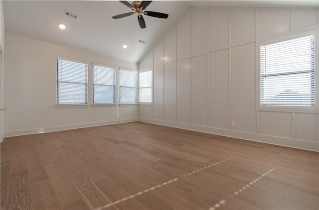 spare room featuring ceiling fan, plenty of natural light, lofted ceiling, and light wood-type flooring