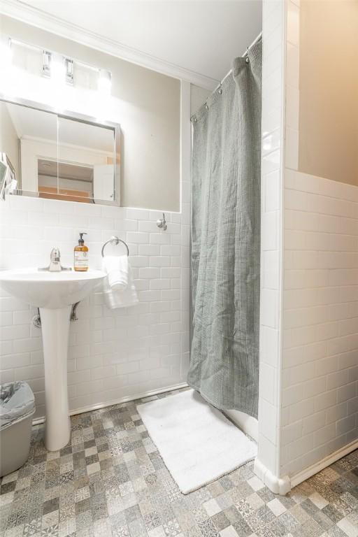 bathroom featuring curtained shower, crown molding, and tile walls