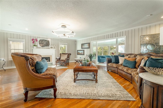 living room featuring crown molding, light hardwood / wood-style floors, and a textured ceiling