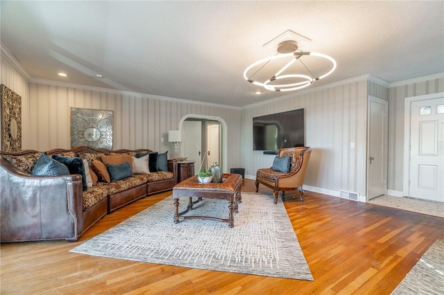 living room featuring wood-type flooring, ornamental molding, and an inviting chandelier