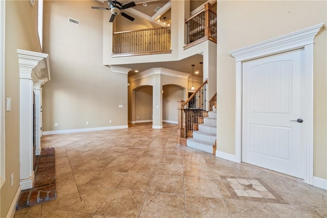 entrance foyer with a towering ceiling, ceiling fan, and ornamental molding