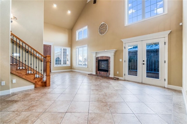 unfurnished living room with a fireplace, french doors, light tile patterned flooring, and a high ceiling