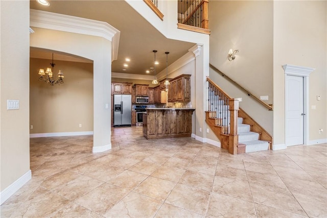 kitchen featuring pendant lighting, ornamental molding, stainless steel appliances, and a chandelier