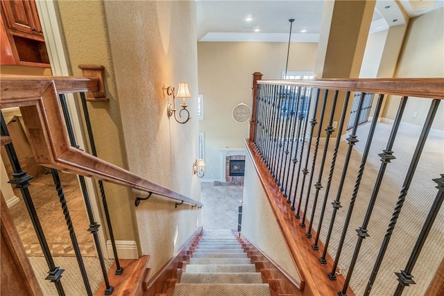 stairs featuring ornamental molding, a fireplace, and carpet floors