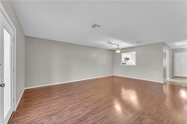 empty room featuring hardwood / wood-style floors, ceiling fan, and a textured ceiling