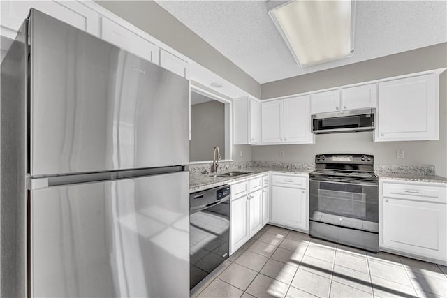 kitchen featuring sink, light tile patterned floors, light stone counters, white cabinets, and black appliances