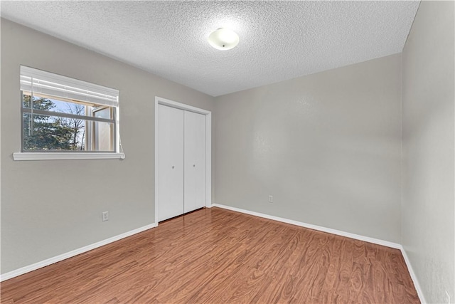 unfurnished bedroom with light wood-type flooring, a textured ceiling, and a closet