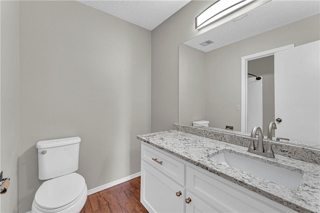 bathroom with vanity, wood-type flooring, a textured ceiling, and toilet