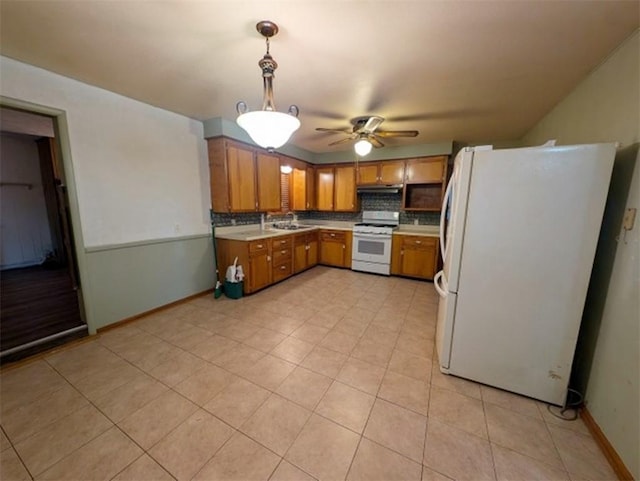 kitchen with white appliances, brown cabinetry, a sink, light countertops, and tasteful backsplash