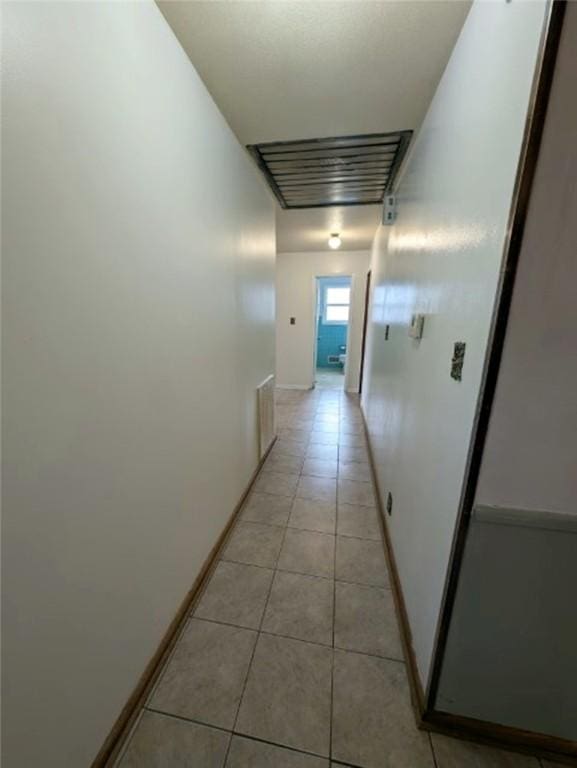 corridor featuring visible vents, baseboards, and light tile patterned flooring