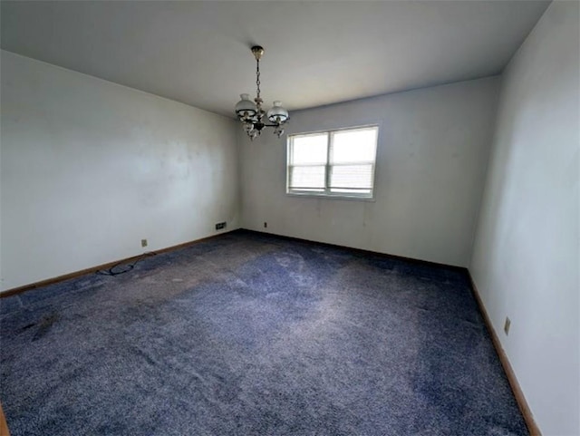 spare room with a notable chandelier, carpet, and baseboards