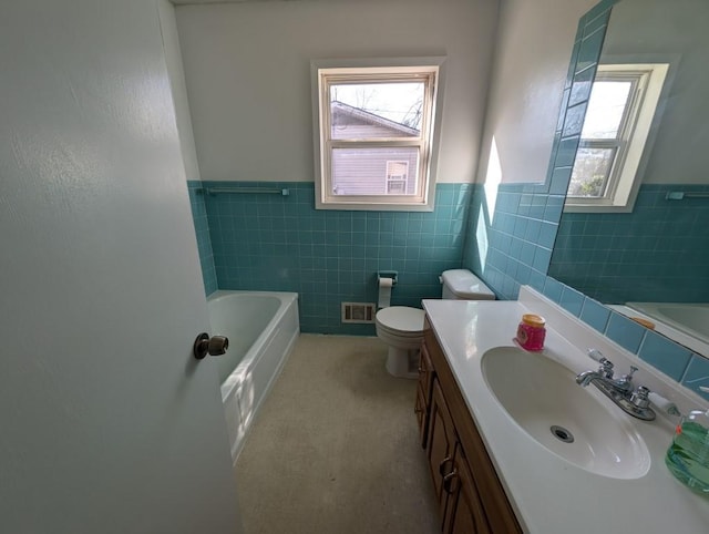 bathroom featuring visible vents, plenty of natural light, vanity, and a tub to relax in