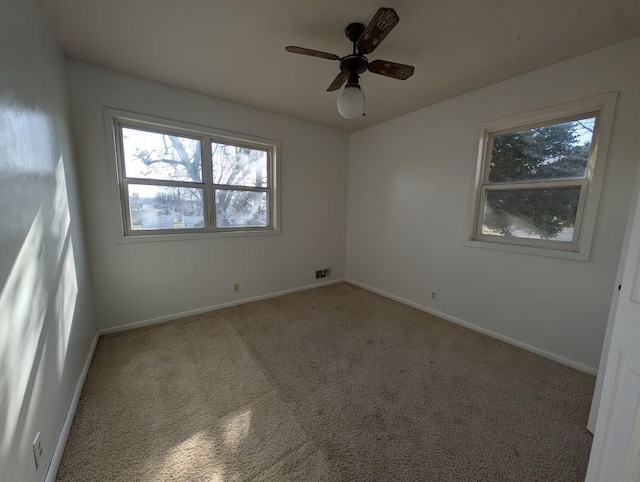 carpeted empty room with visible vents, baseboards, and a ceiling fan