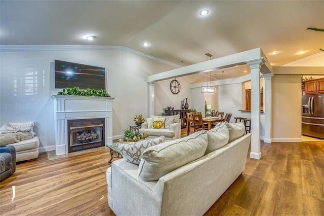 living room with ornamental molding, lofted ceiling, and hardwood / wood-style floors